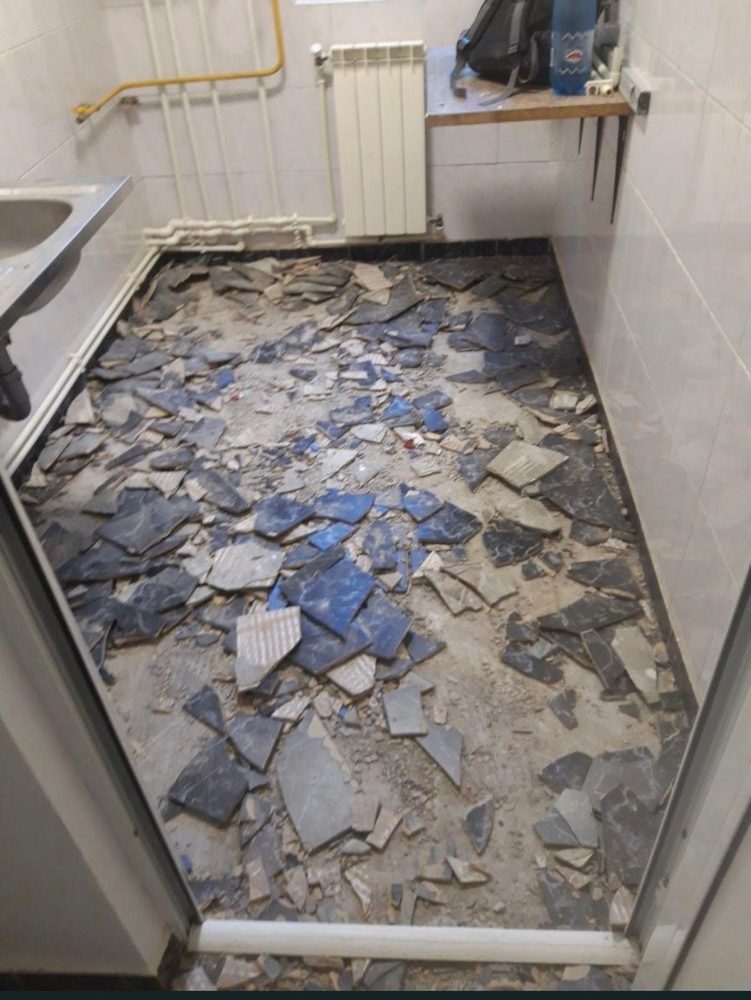 Gresie desfăcută de pe pardoseala unei bucătării, cu reziduurile adunate