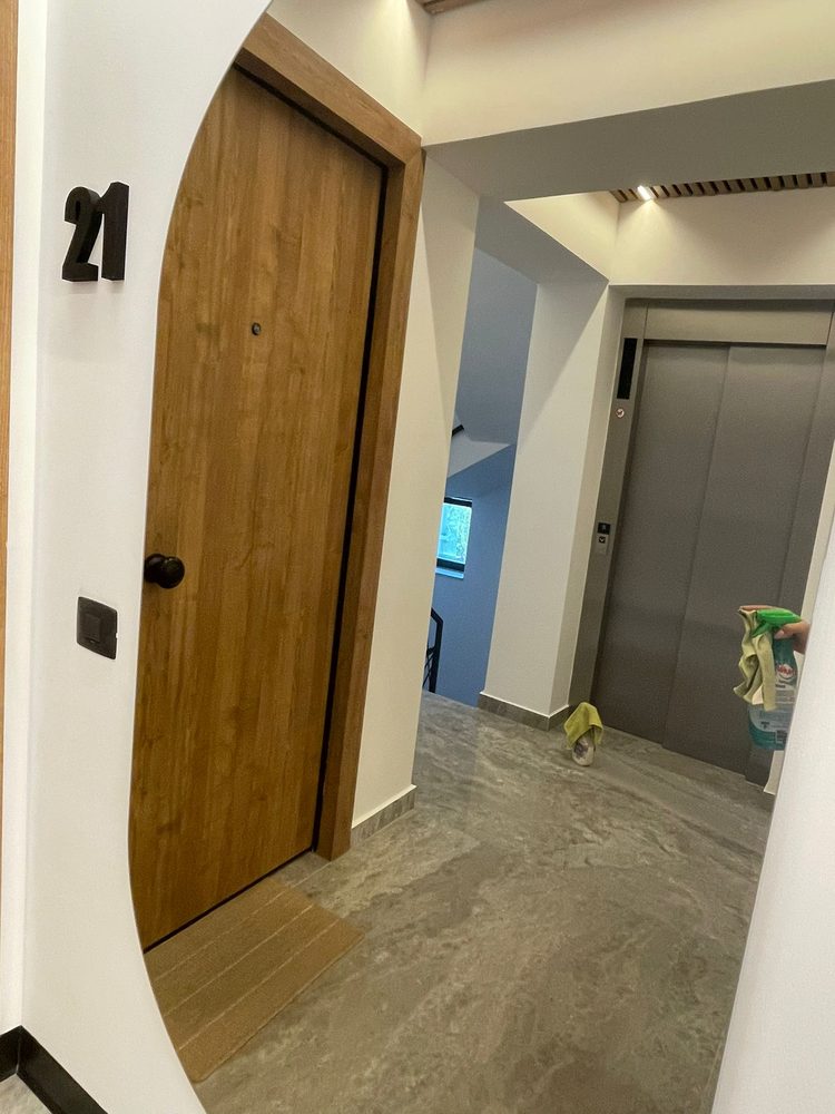 Hol de acces dintr-o locuință, cu ușa liftului interior și pardoseala curățate