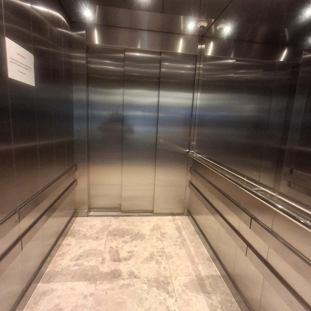 Interiorul unui lift de marfă din inox, cu pardoseala murdară înainte de intervenție