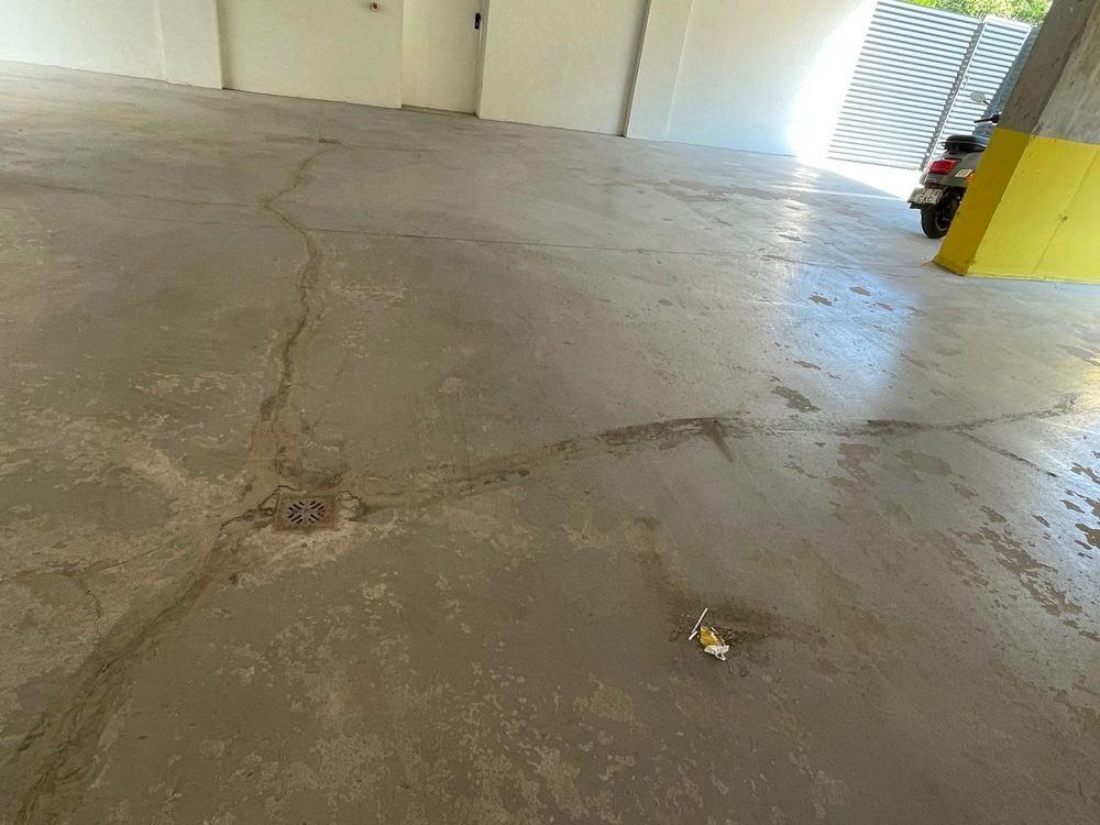 Pardoseală de beton dintr-o parcare acoperită, cu depuneri, înainte de spălarea mecanizată